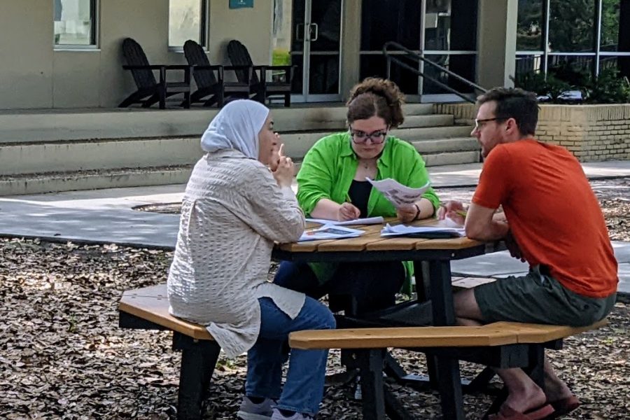 3 workshop participants in conversation outside around a picnic table