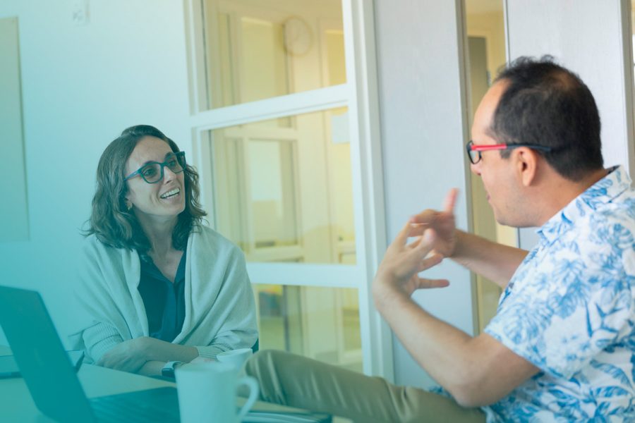 Man and woman facing each other across a table while taking notes and talking